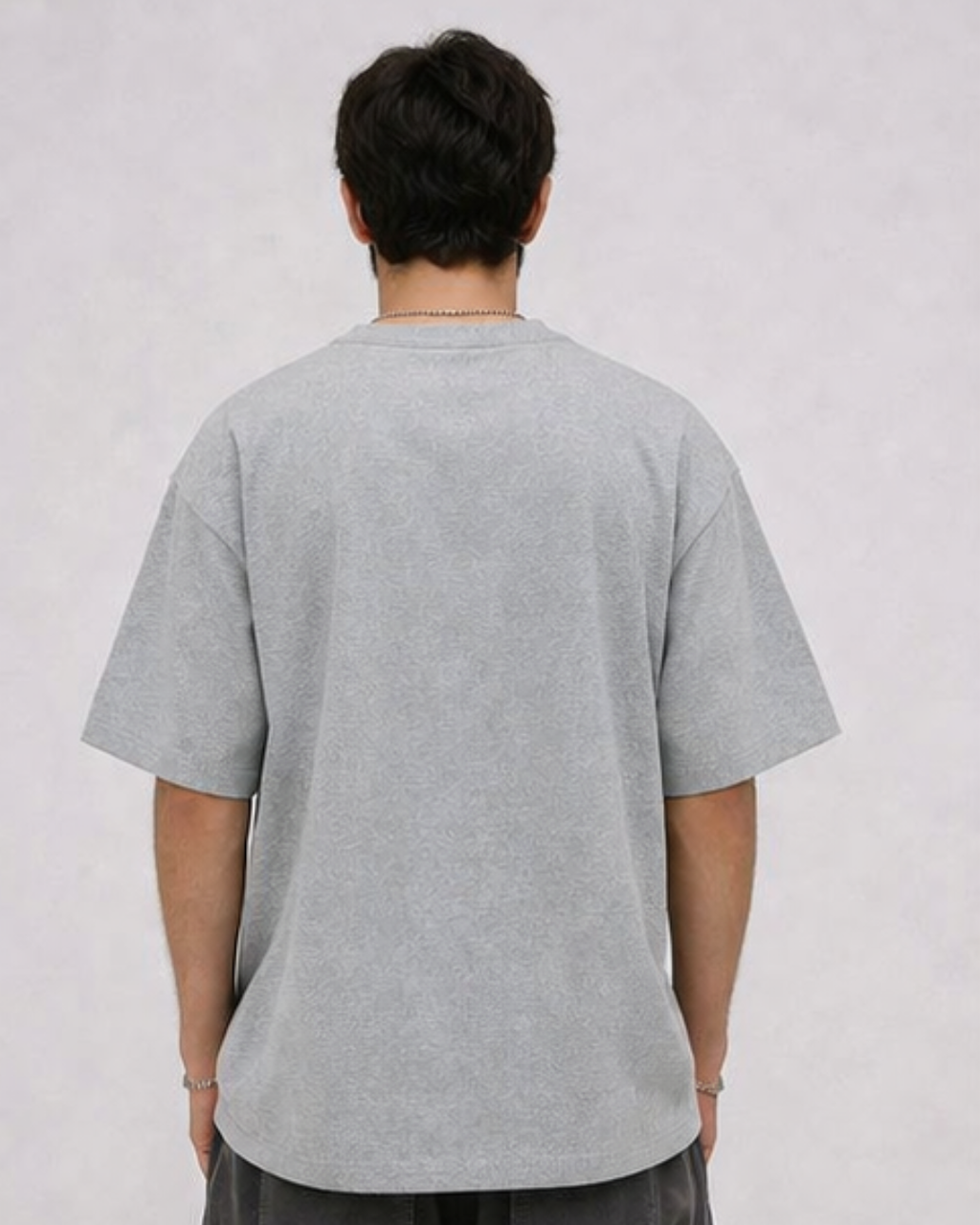 Person wearing a grey t-shirt on a plain background