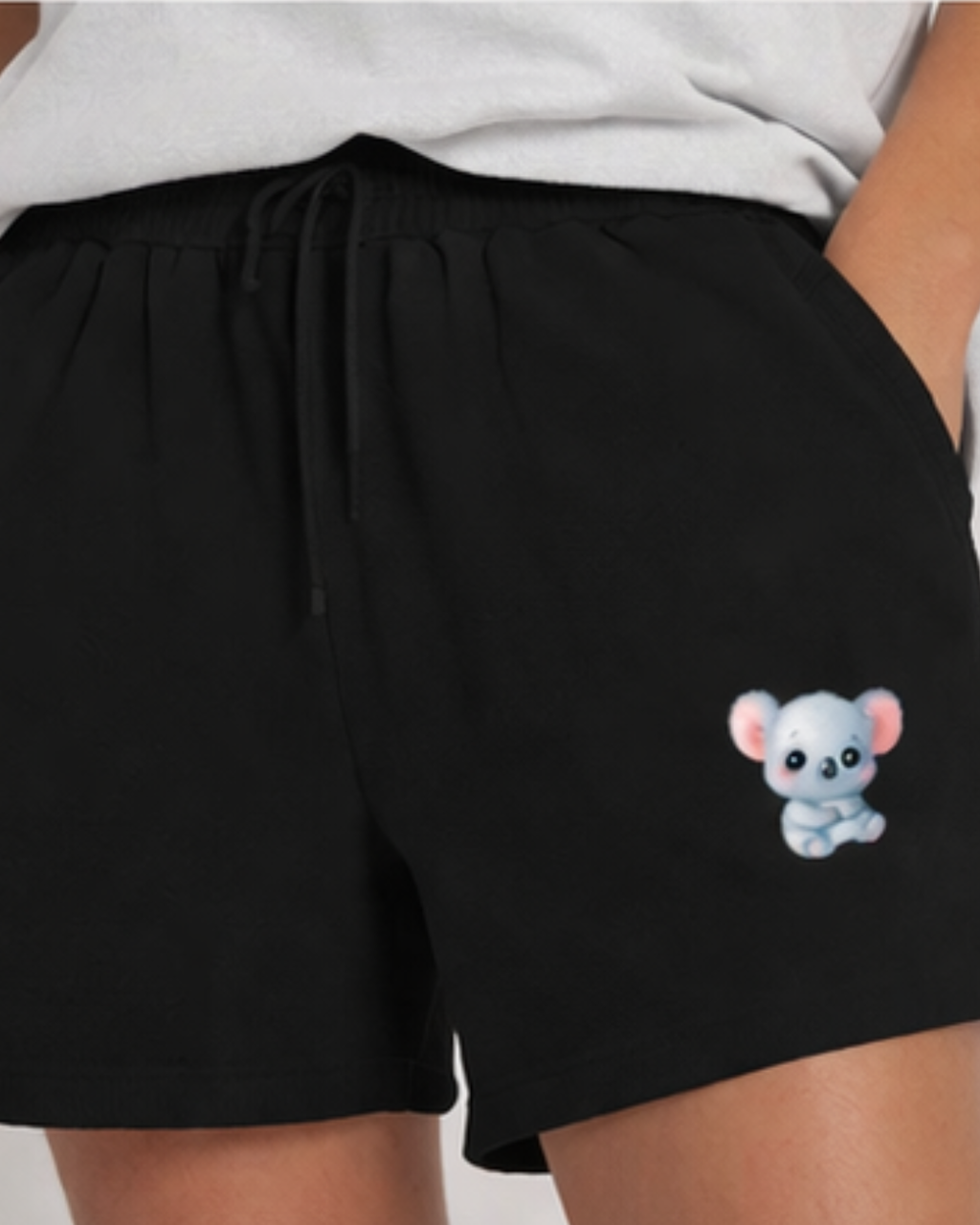 Black shorts with a cartoon koala design on the pocket worn by a person.