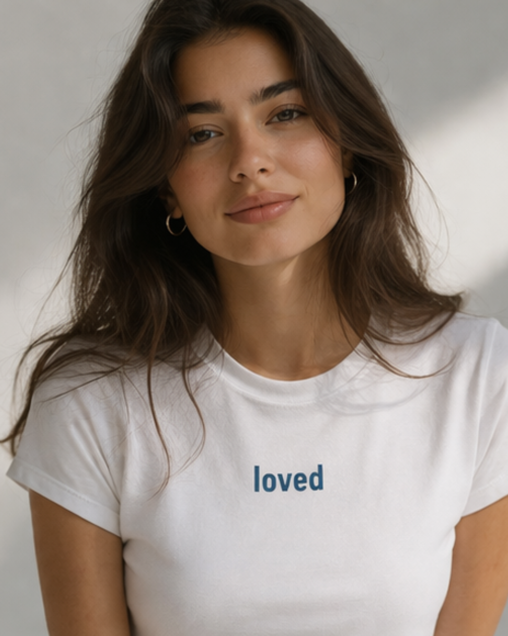 Woman wearing a white t-shirt with 'loved' text on a plain background