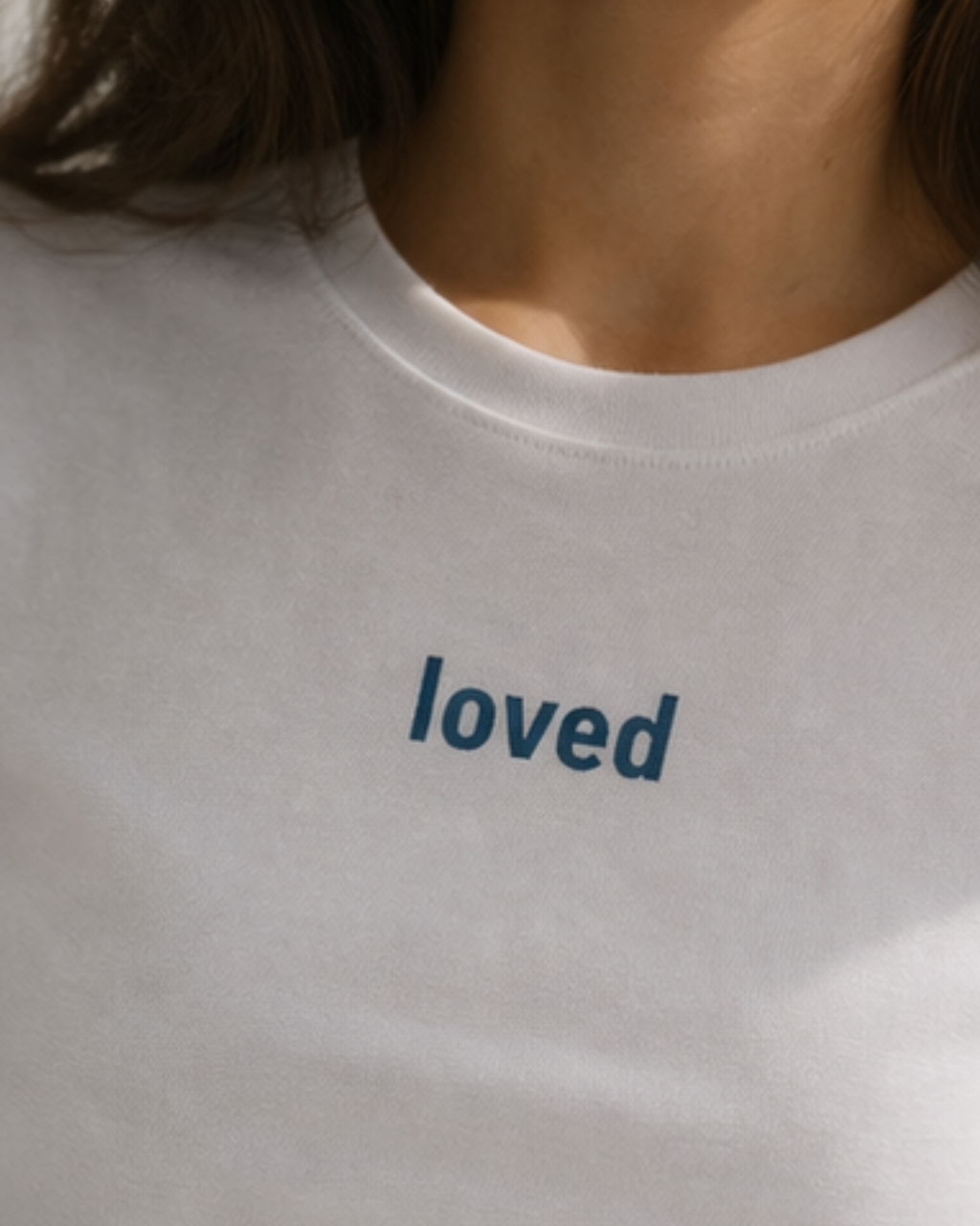 White t-shirt with 'loved' text on a plain background