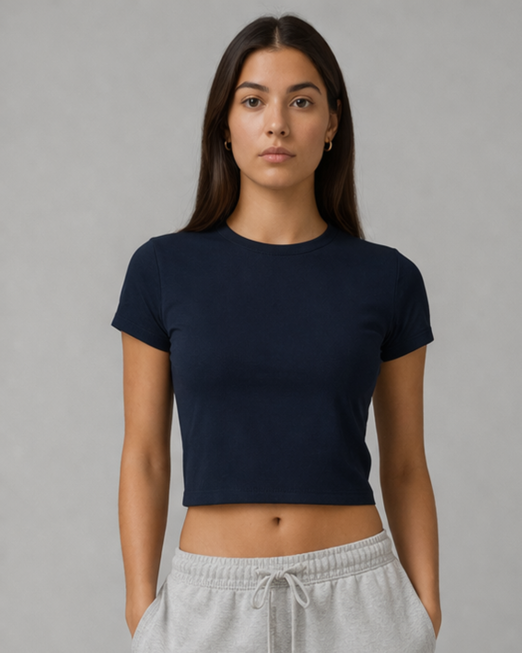 Woman wearing a navy blue t-shirt and gray sweatpants against a plain background