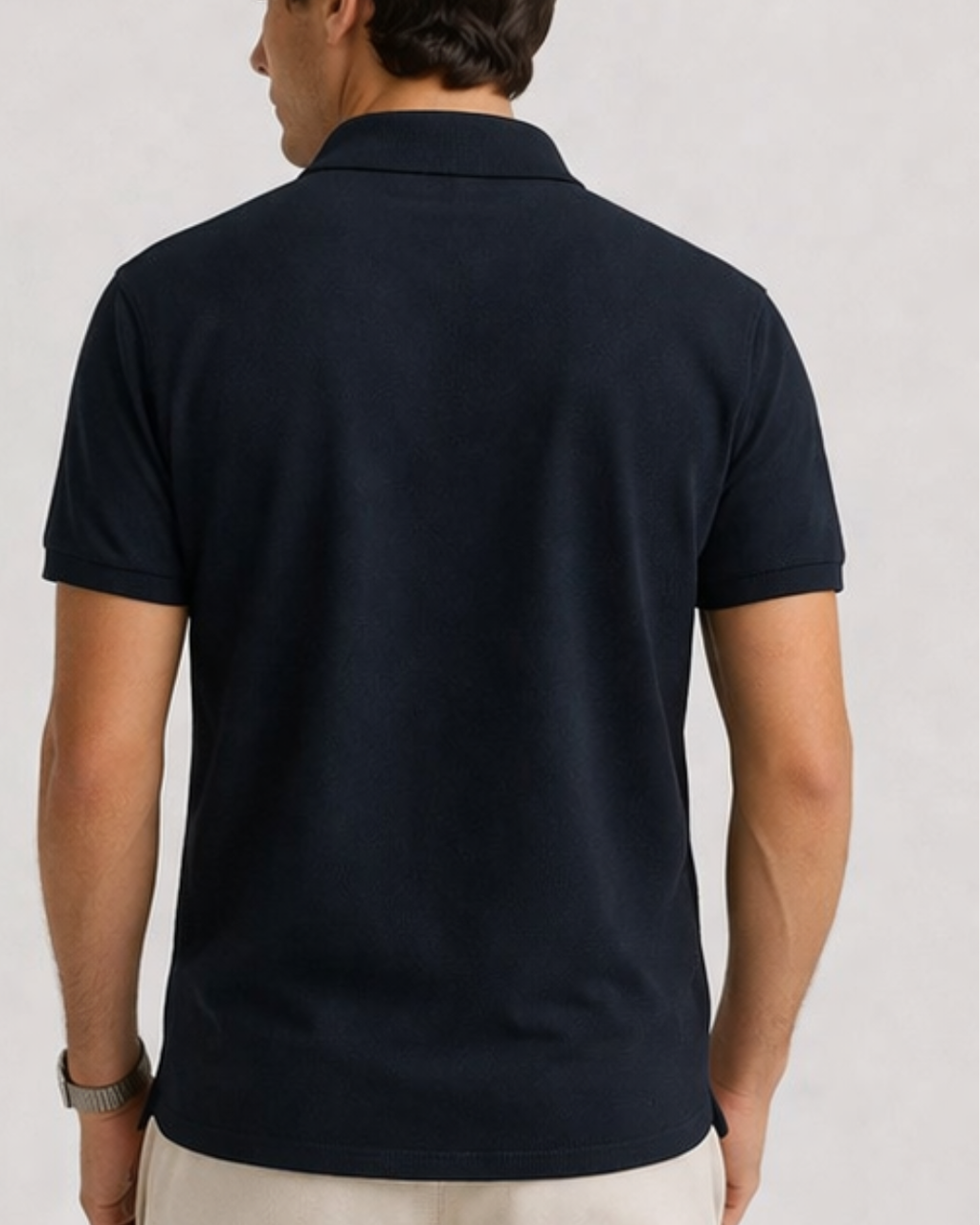 Man wearing a navy blue polo shirt on a light gray background