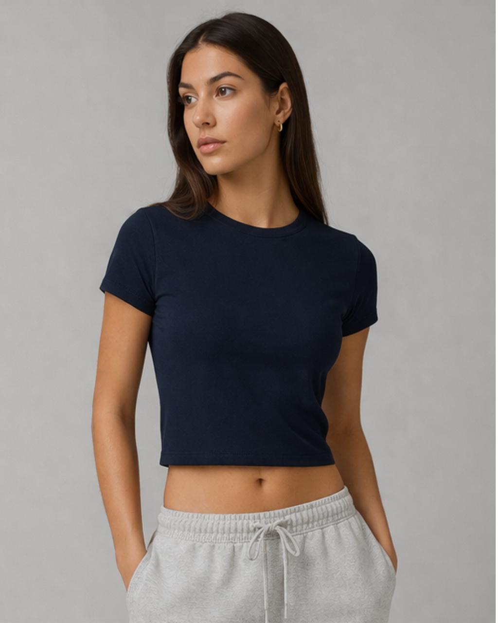 Woman wearing a navy blue t-shirt and gray sweatpants against a gray background