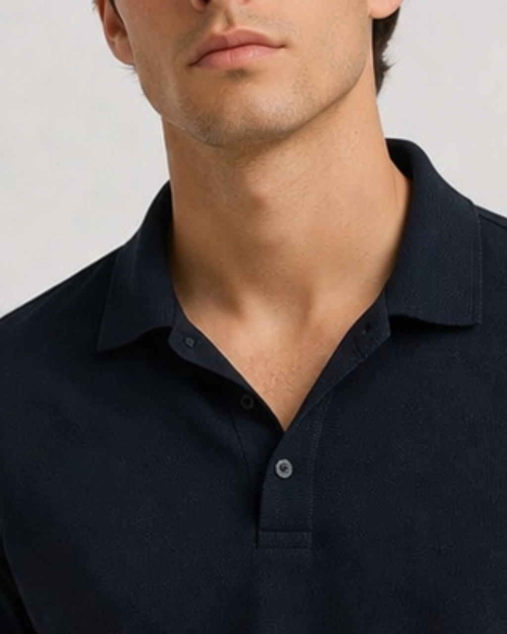 Man wearing a dark blue polo shirt against a light background