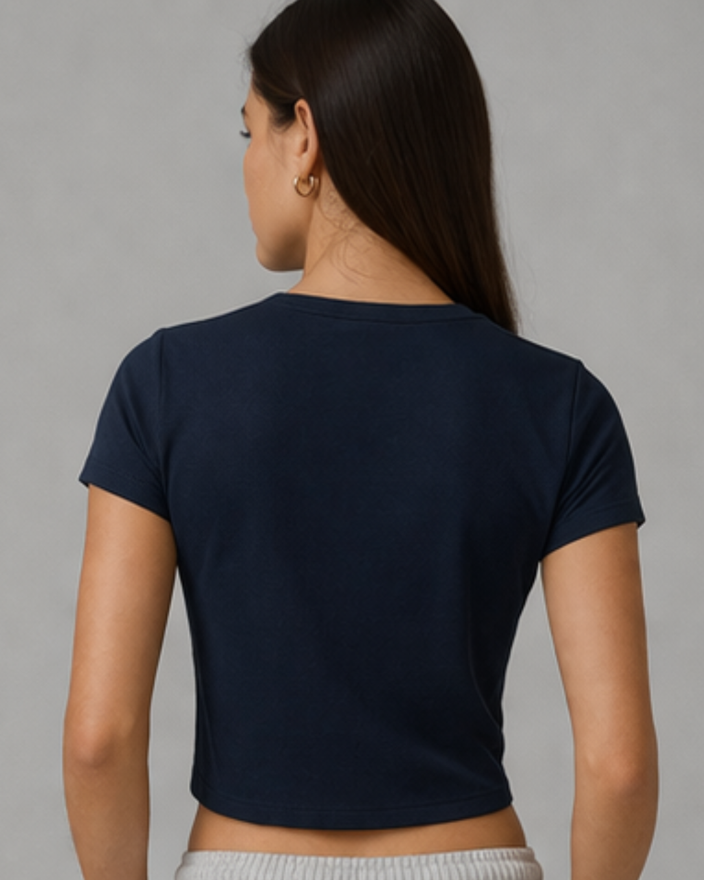 Woman wearing a navy blue crop top against a gray background