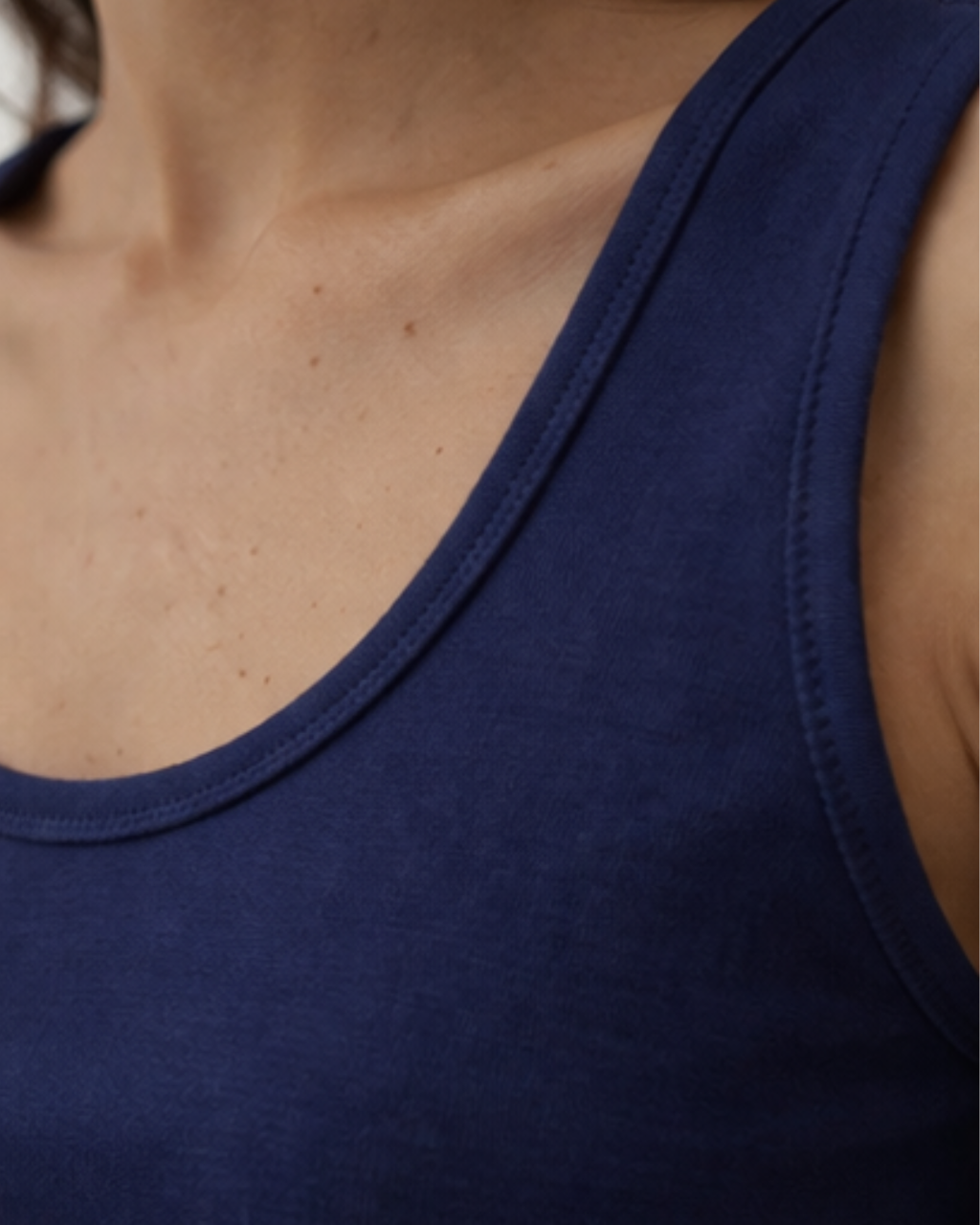 Close-up of a person wearing a navy blue tank top.