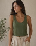 Woman wearing a green tank top and beige pants against a neutral background