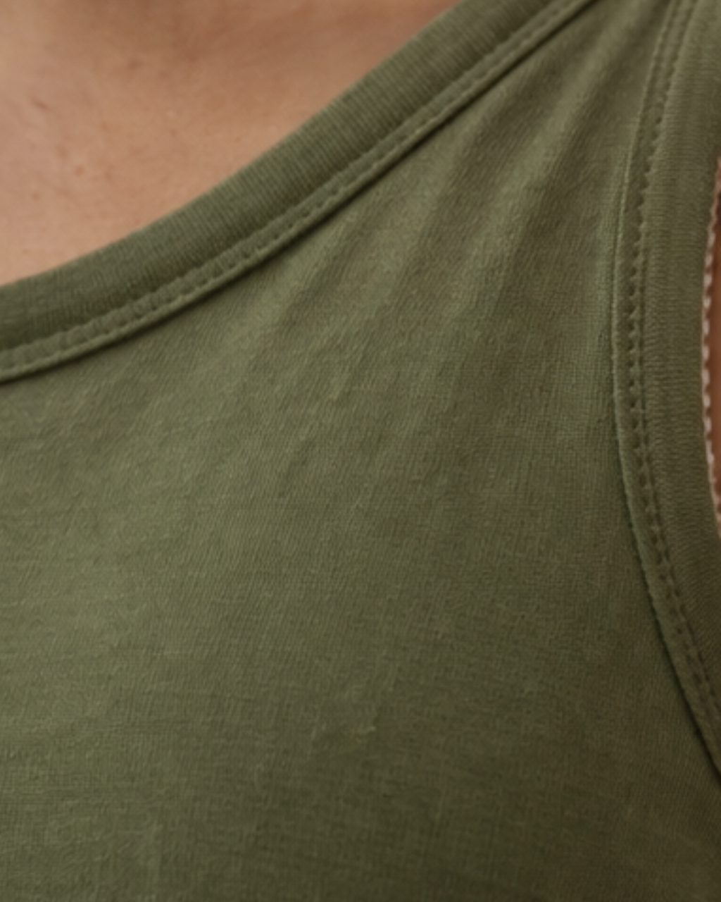 Close-up of a green tank top with a focus on the neckline and fabric texture.