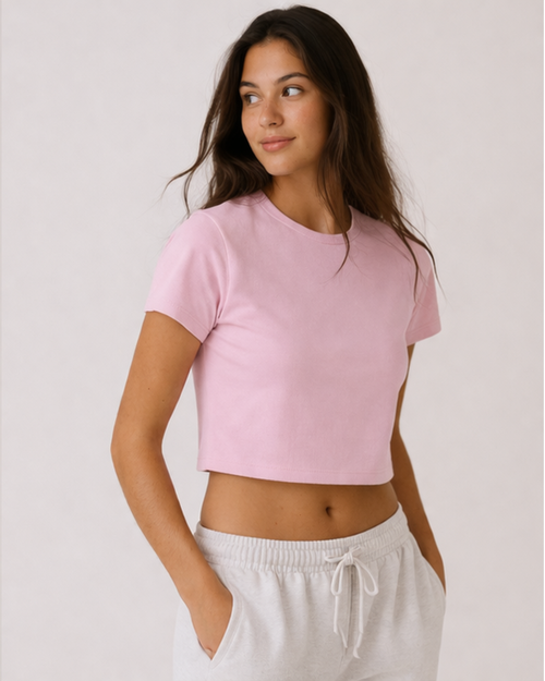 Woman wearing a pink crop top and white pants against a plain background