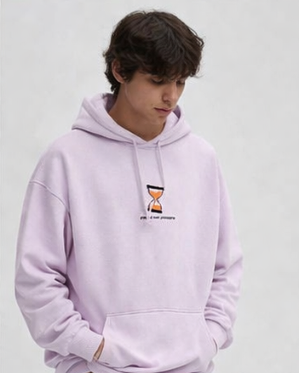 Person wearing a baby pink hoodie with a small logo on a plain background
