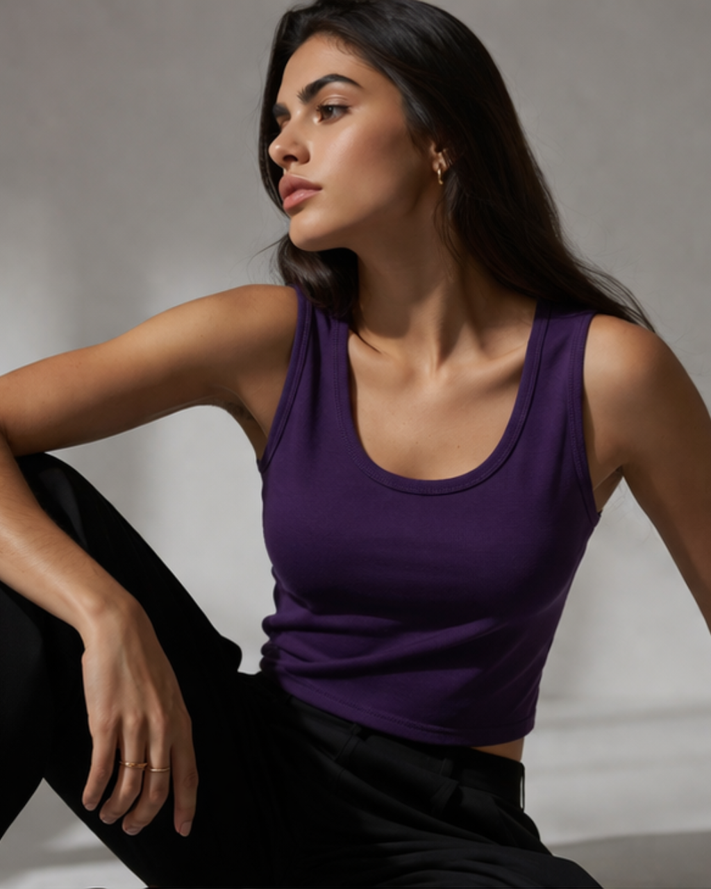 Woman wearing a purple tank top sitting against a neutral background