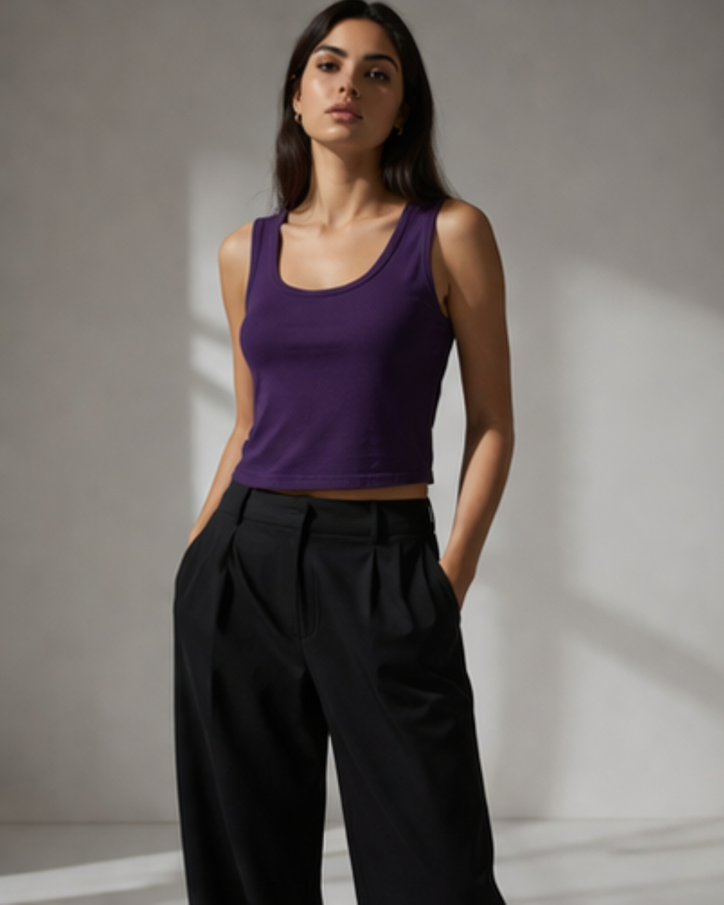 woman wearing purple tank top styled with black formals pant standing on a light background