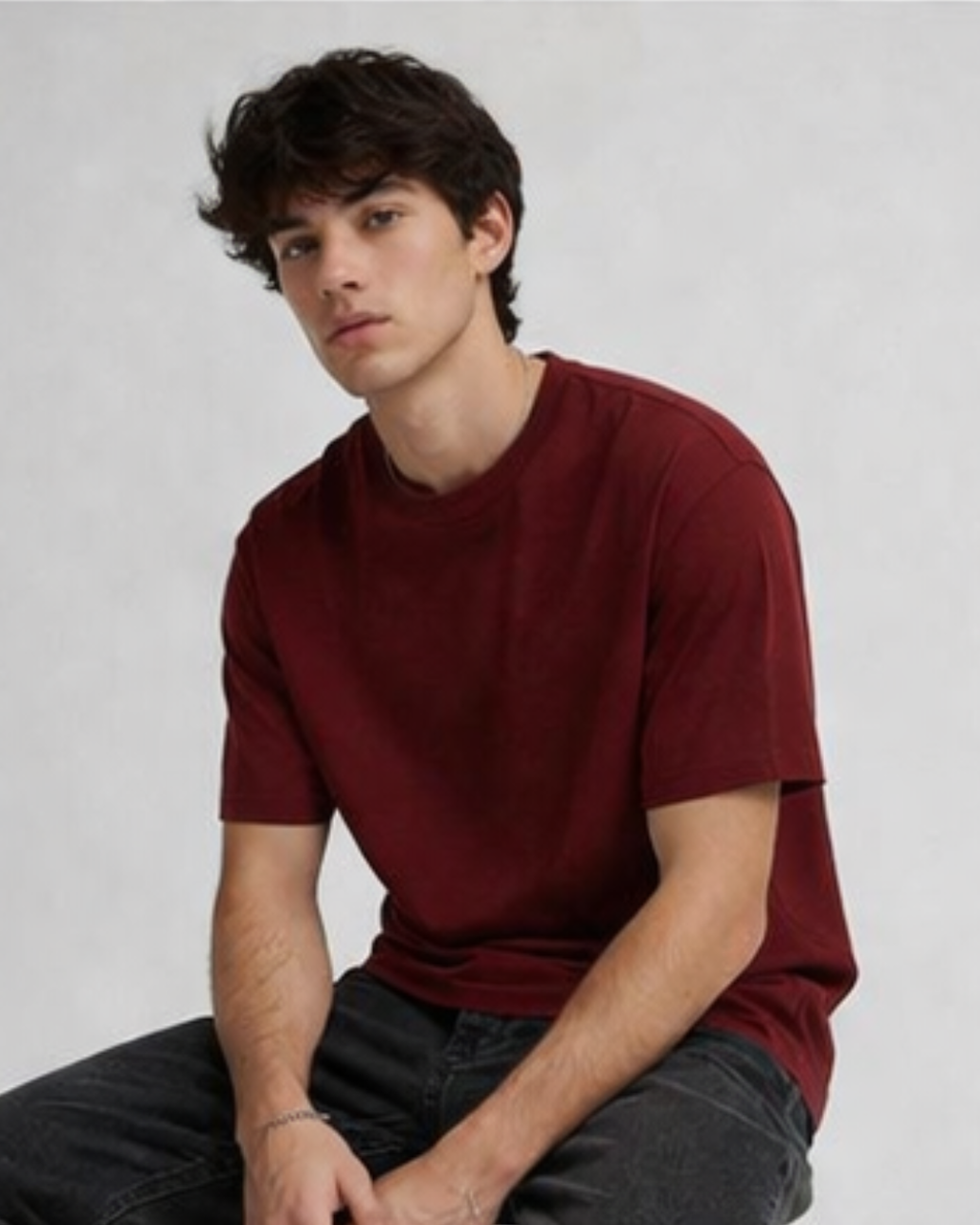 Person wearing a red t-shirt sitting against a plain background