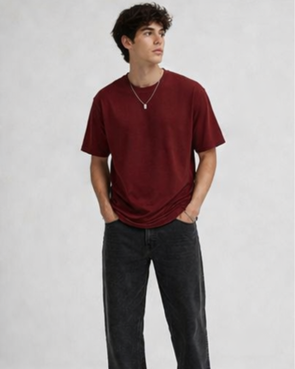 Person wearing a red t-shirt and dark jeans on a plain background