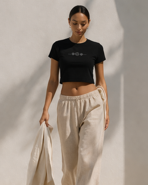 Woman wearing a black crop top and beige pants against a neutral background