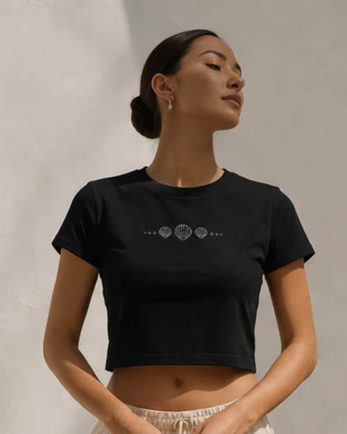 Woman wearing a black cropped t-shirt with a graphic design on a neutral background