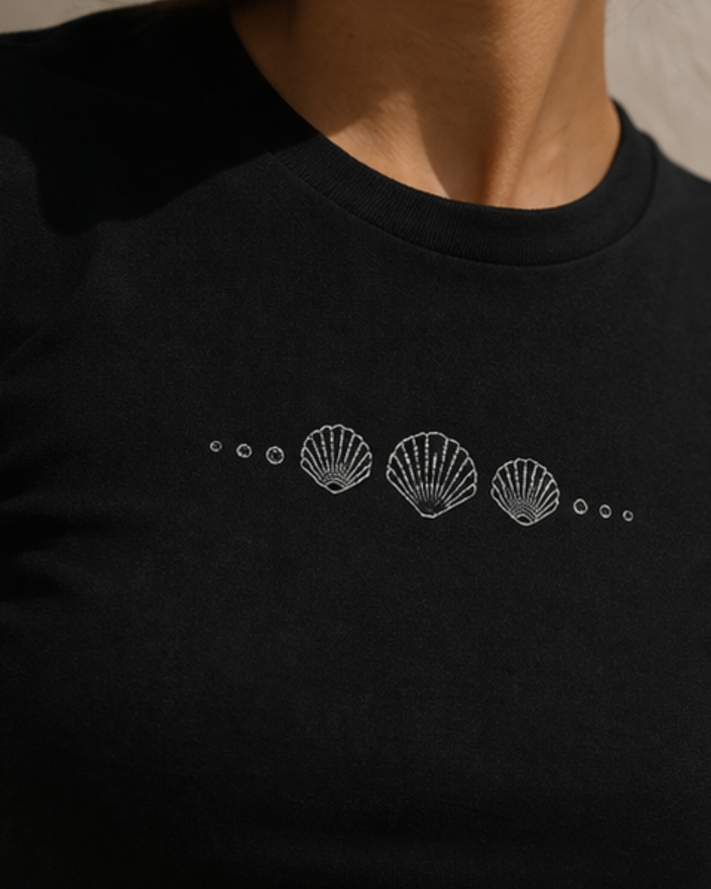 Black crop top with white shell design on a plain background