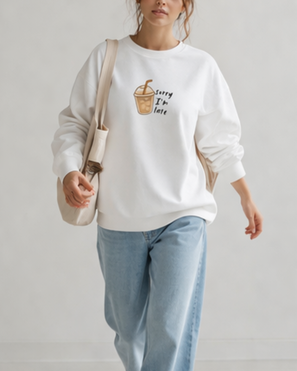 Person wearing a white sweatshirt with a graphic design on a plain background
