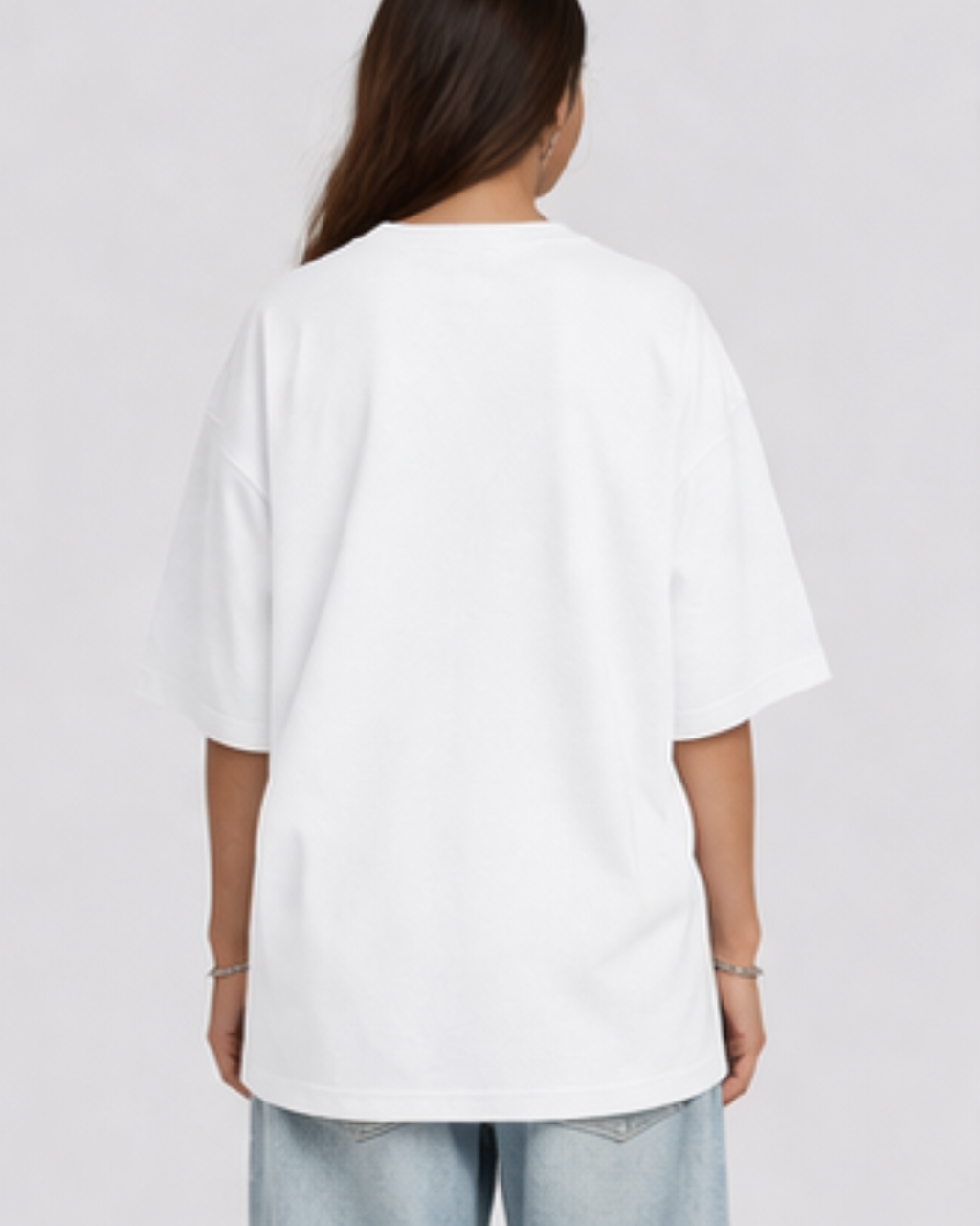 Person wearing a plain white oversized t-shirt on a light gray background