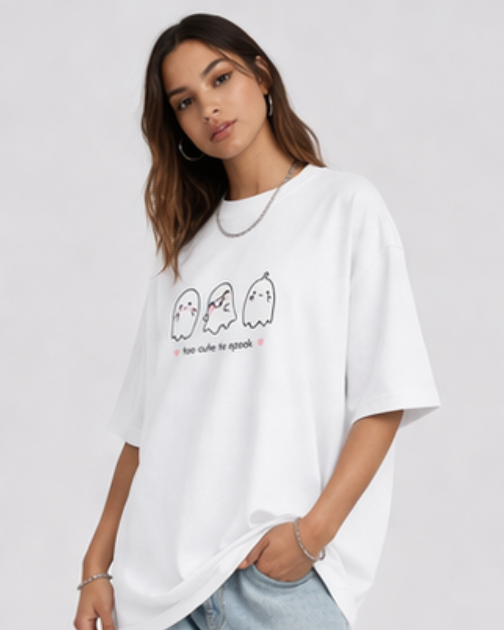 Woman wearing a white oversized t-shirt with ghost graphics and text on a plain background