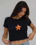 Woman wearing a black crop top with a starfish design on a plain background