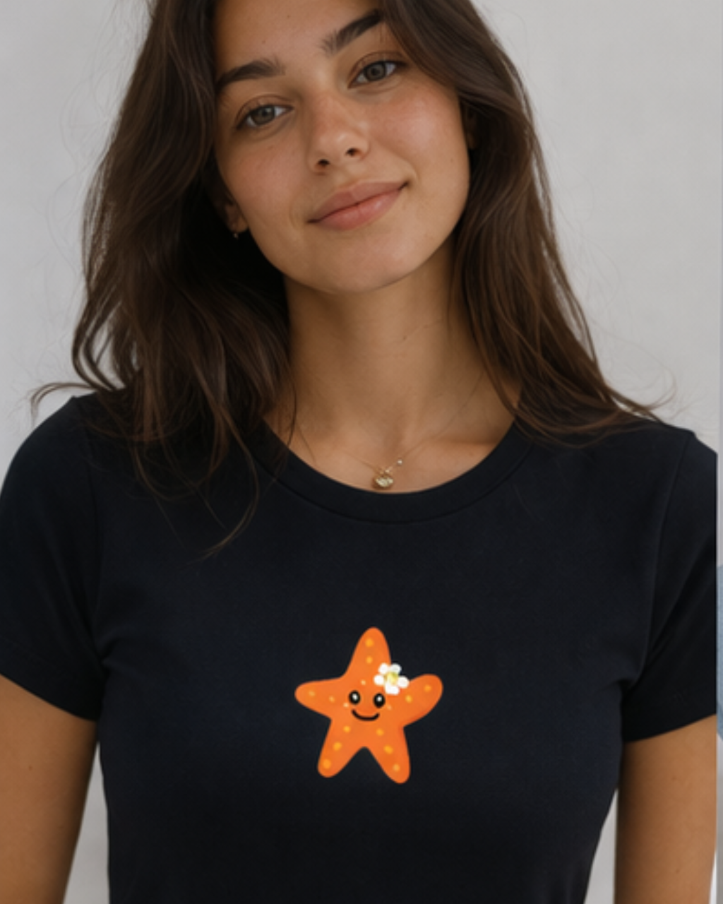 Person wearing a black t-shirt with a smiling starfish design on a plain background