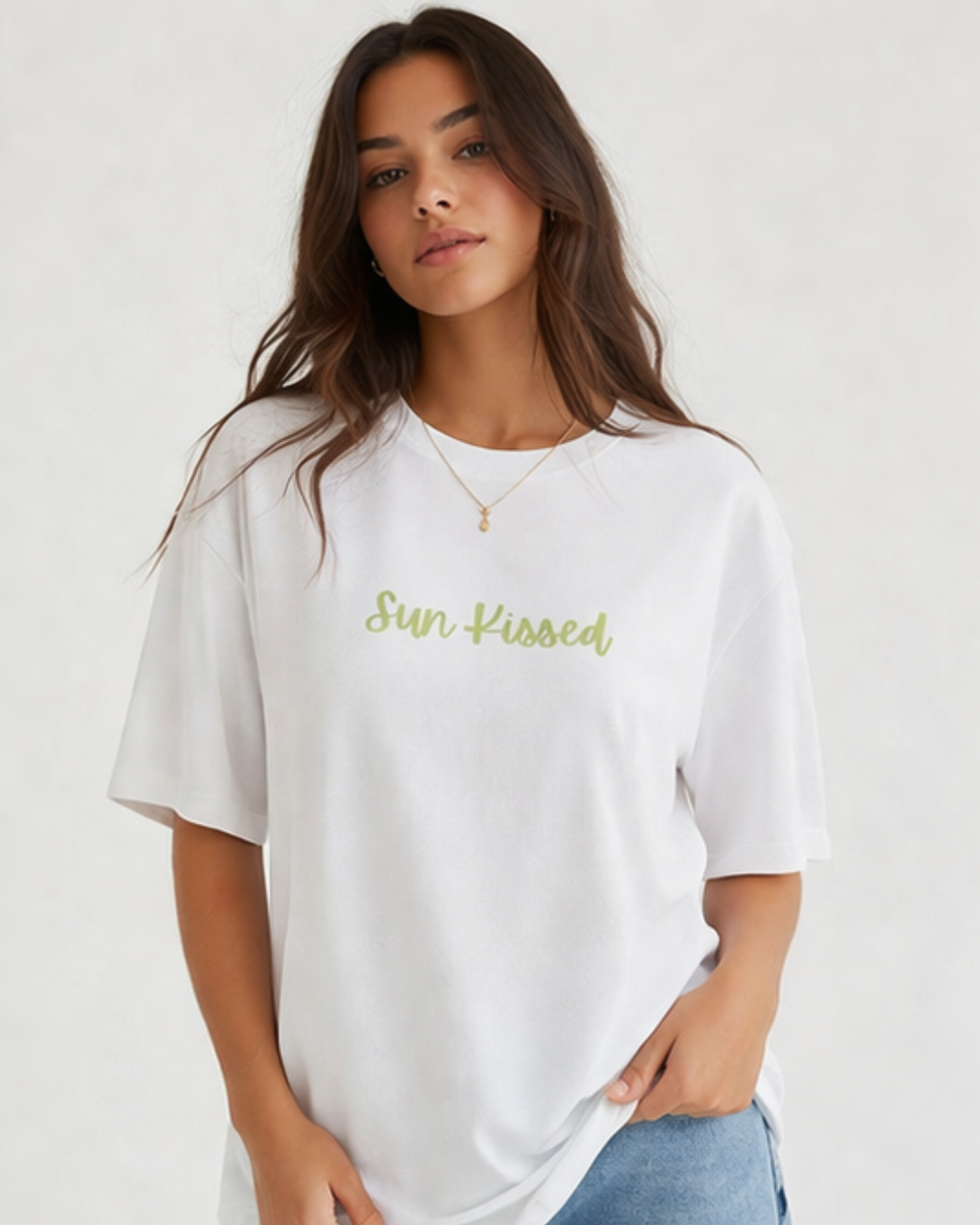 Woman wearing a white oversized t-shirt with 'Sun Kissed' text on a plain background