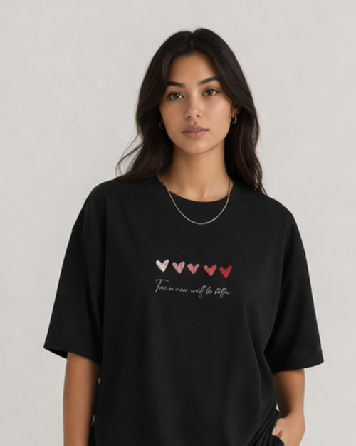 Woman wearing a black t-shirt with heart designs and text on a plain background