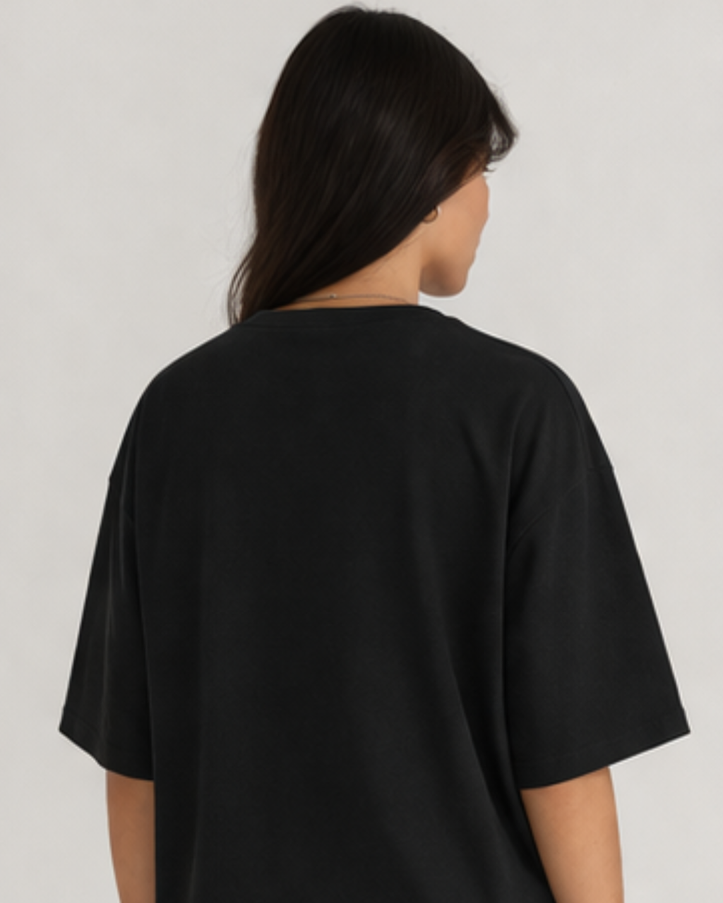 Person wearing a black oversized t-shirt against a plain background