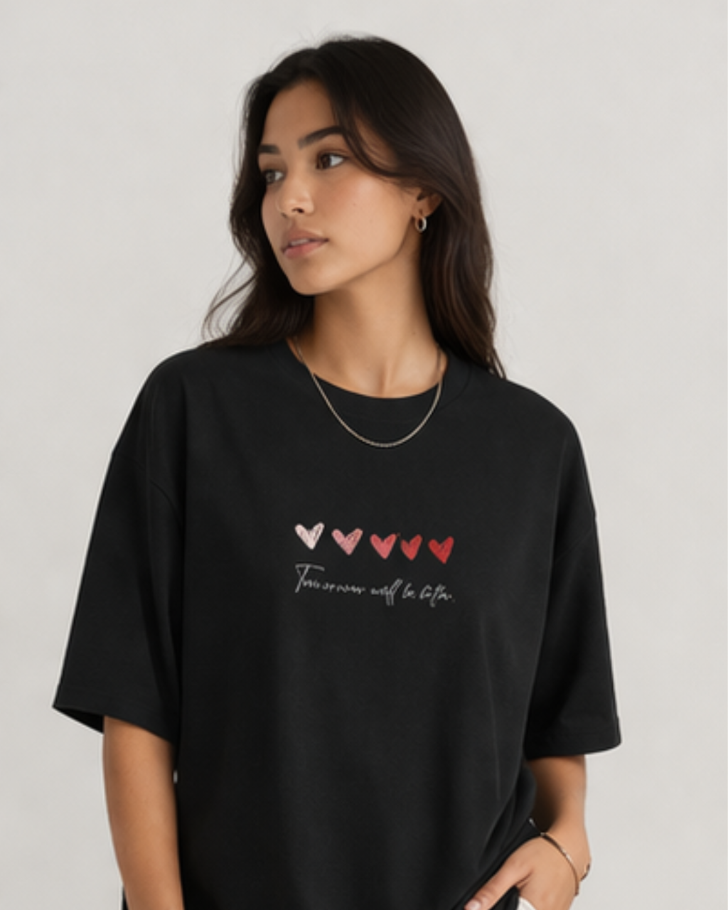 Woman wearing a black t-shirt with heart designs and text on a plain background