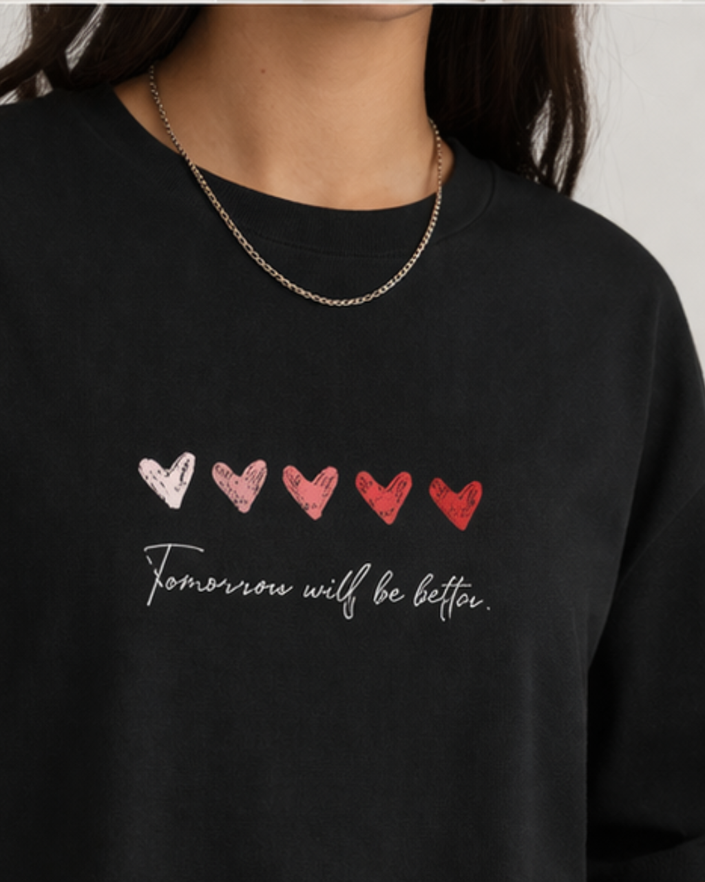 Black oversized t-shirt with heart designs and text 'Tomorrow will be better' on a plain background