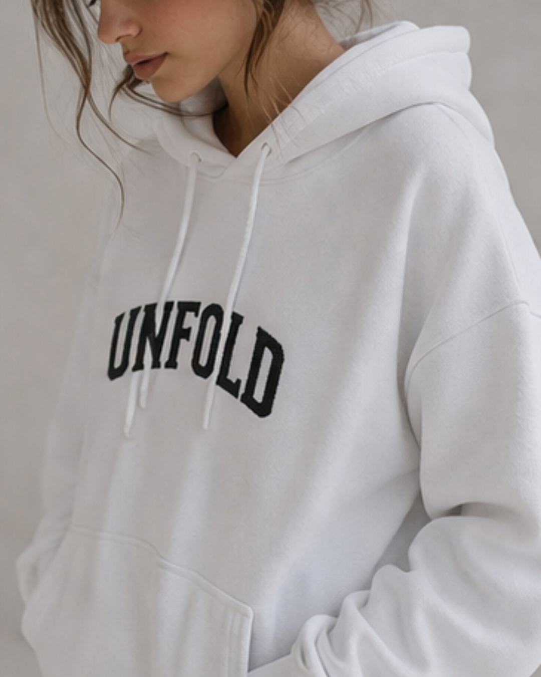 White hoodie with 'UNFOLD' text on a neutral background