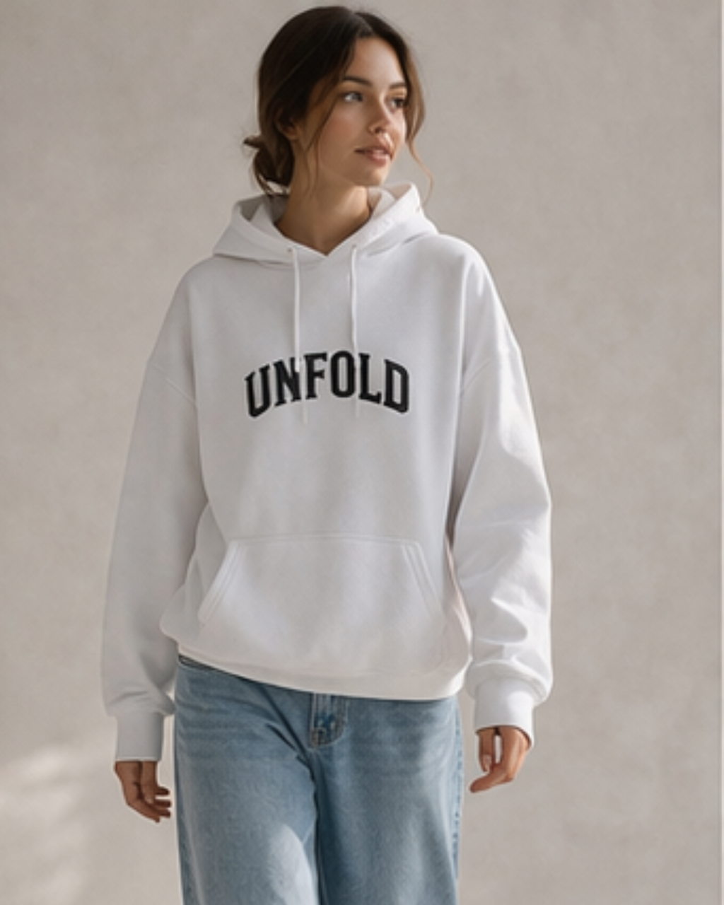 Person wearing a white hoodie with 'UNFOLD' text on a plain background