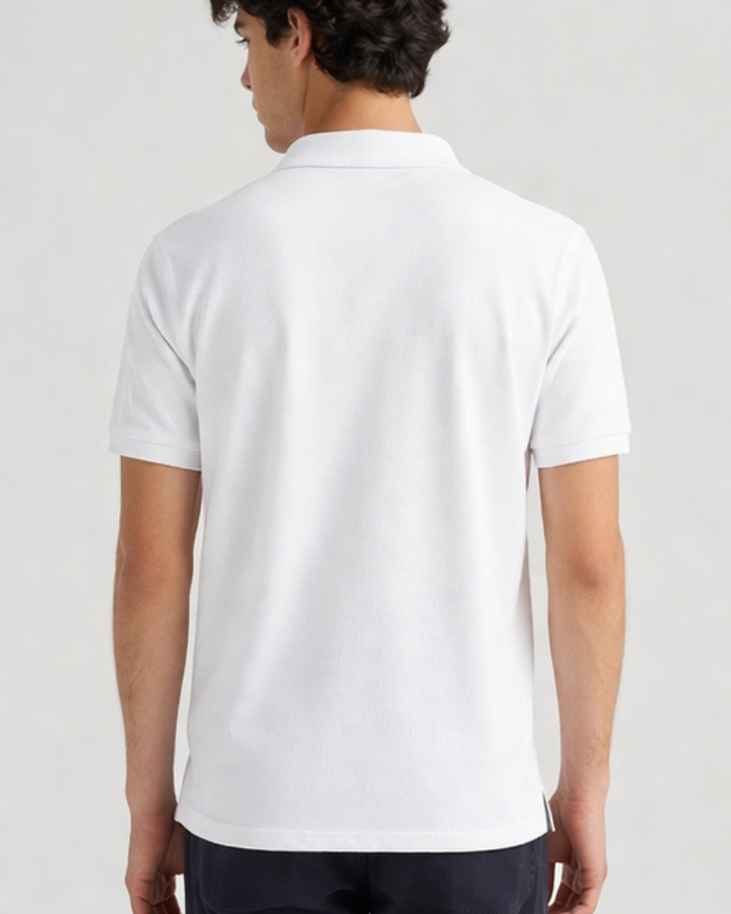 Person wearing a white polo shirt on a plain background