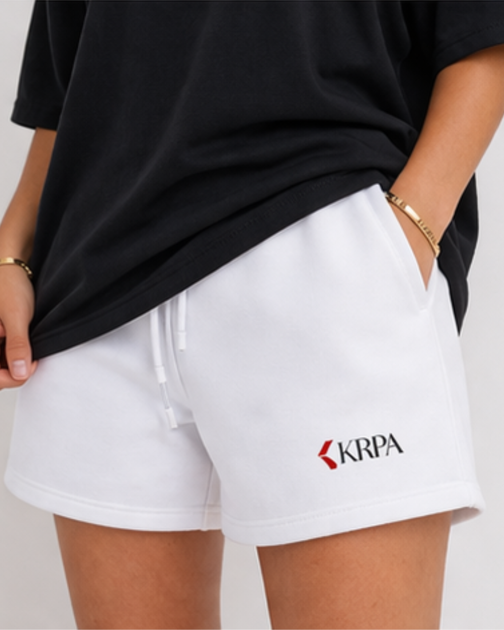 Person wearing white shorts with KRPA logo and text, standing against a neutral background