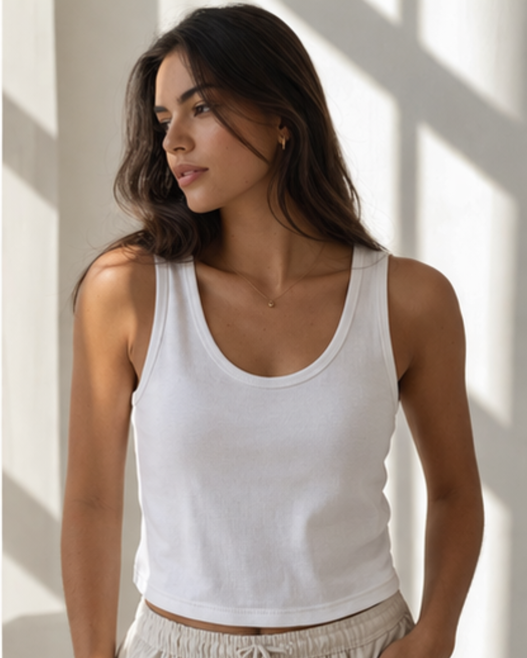 Woman wearing a white tank top against a neutral background