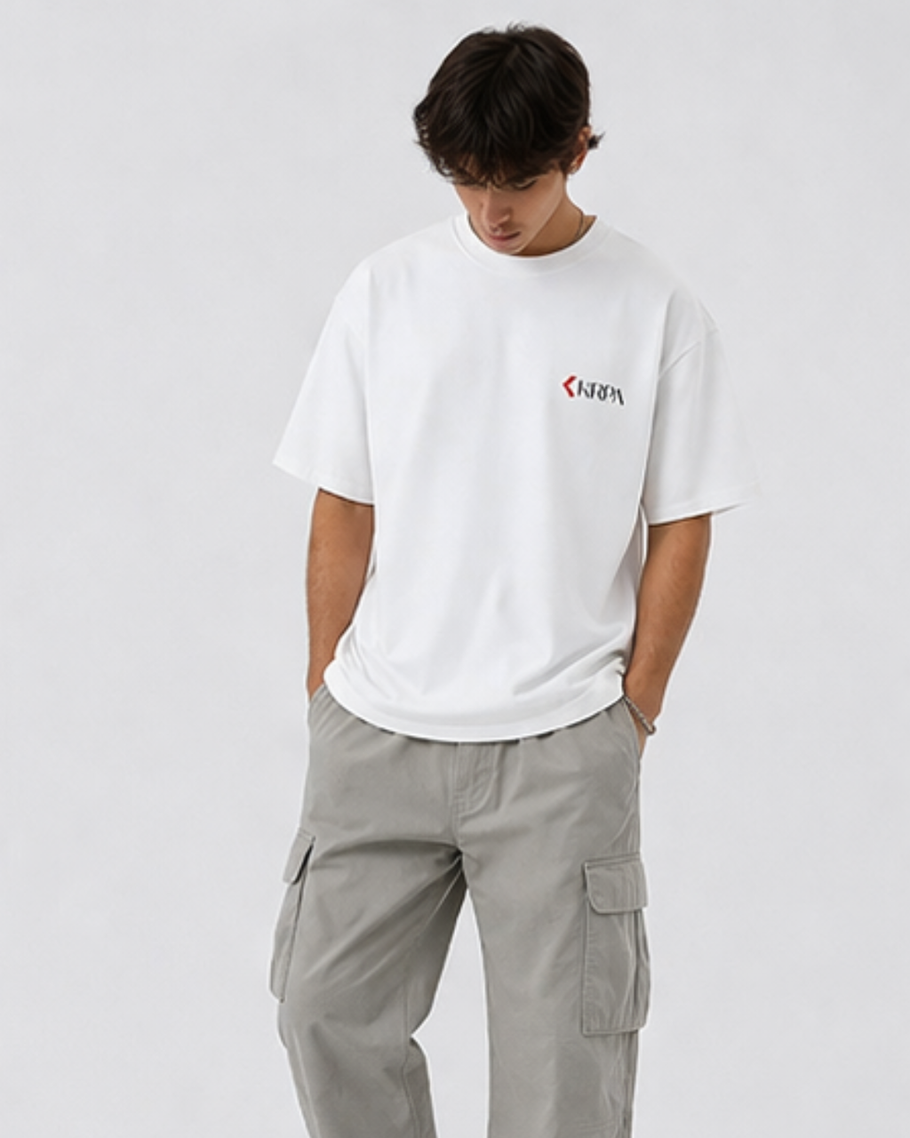 Person wearing a white t-shirt with KRPA logo and gray cargo pants on a light gray background