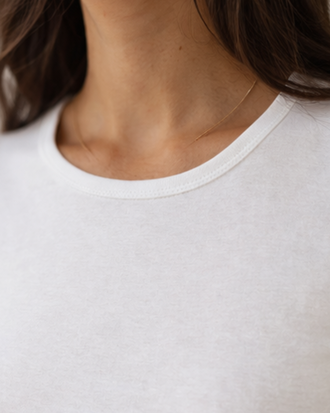 Close-up of a person wearing a plain white t-shirt with a neutral background